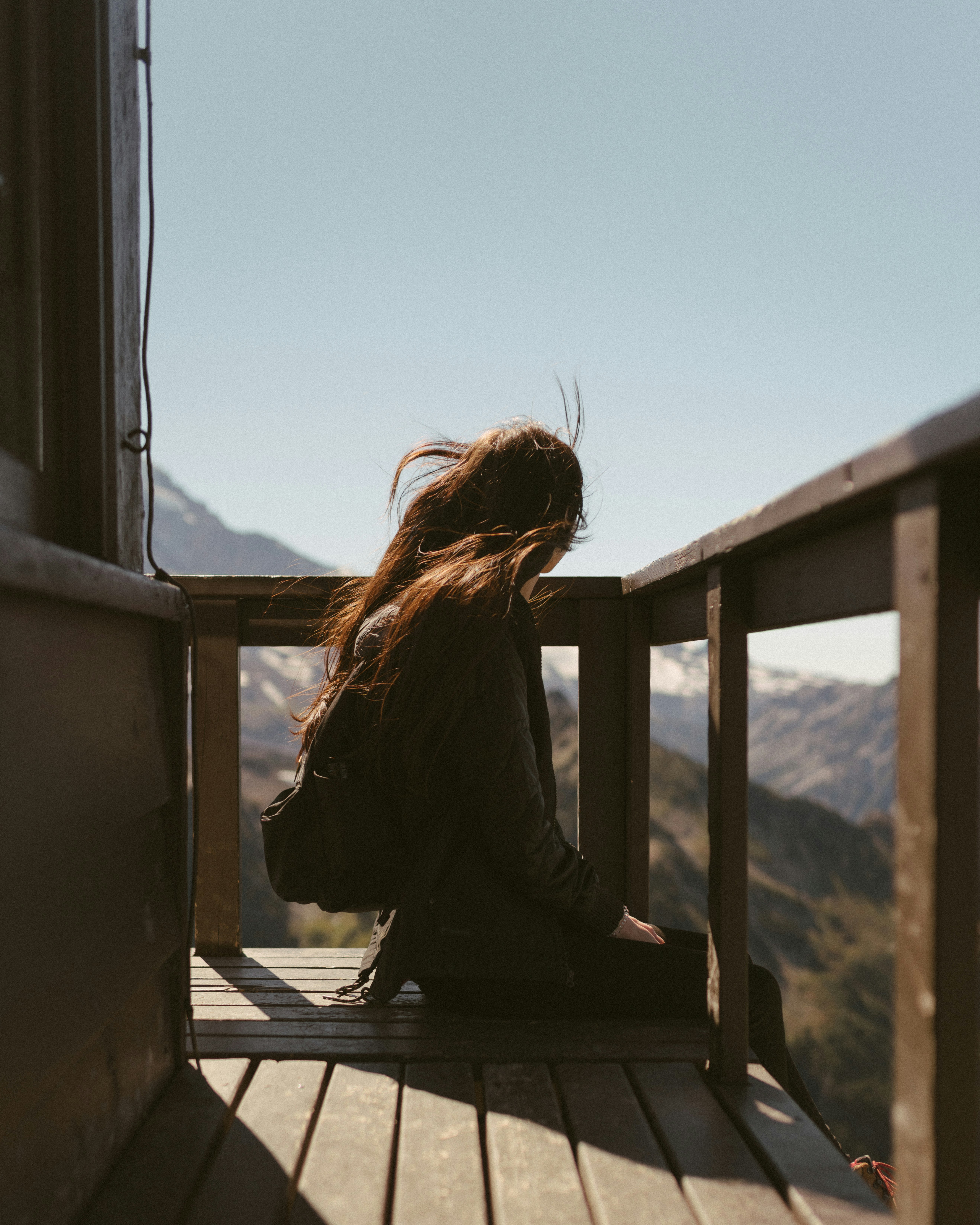 woman in black long sleeve shirt sitting on brown wooden bench during daytime